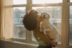 A lady carrying and giving a kiss to her puppy